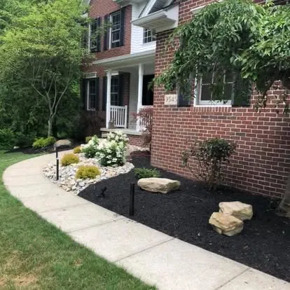 Brick home mulch bed with rock border and curved walkway